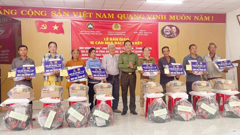 Lãnh đạo phòng An ninh nội địa Công an tỉnh An Giang và đại diện nhà hảo tâm, trao tặng nhà đại đoàn kết và quà cho các hộ gia đình.