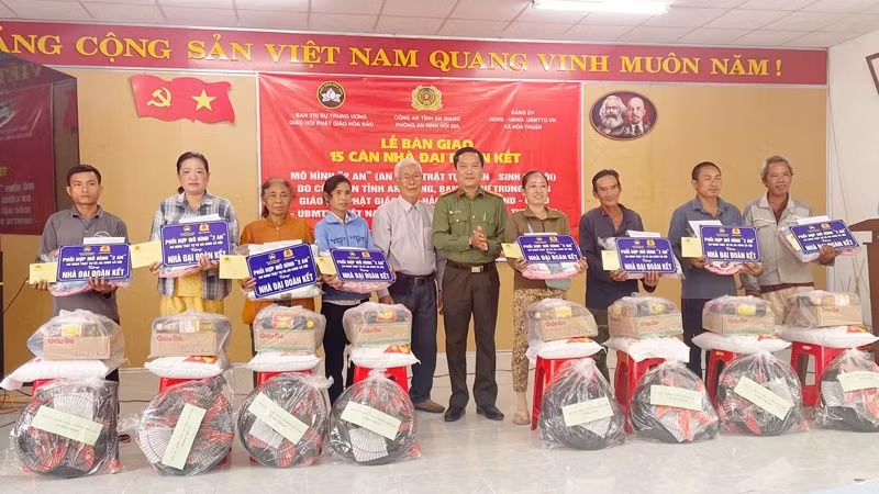 Lãnh đạo phòng An ninh nội địa Công an tỉnh An Giang và đại diện nhà hảo tâm, trao tặng nhà đại đoàn kết và quà cho các hộ gia đình.