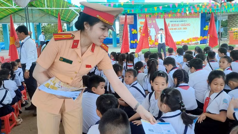 Cán bộ Cảnh sát giao thông phát tờ rơi tuyên truyền tại Trường tiểu học Tân Hưng Tây A, xã Nguyễn Việt Khái, tỉnh Cà Mau.