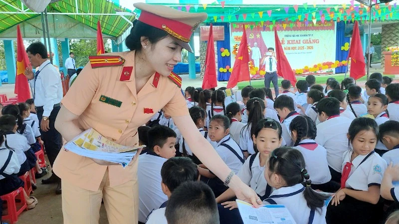 Cán bộ Cảnh sát giao thông phát tờ rơi tuyên truyền tại Trường tiểu học Tân Hưng Tây A, xã Nguyễn Việt Khái, tỉnh Cà Mau.