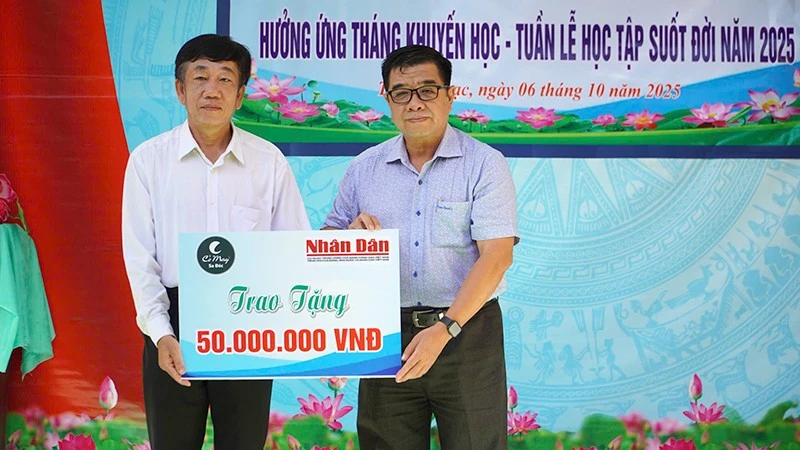 Ông Phạm Hữu Hoàn (bìa phải), đại diện Quỹ Xã hội Cỏ May trao 50 triệu đồng do Báo Nhân Dân vận động Quỹ để hỗ trợ học bổng tặng học sinh phường Thường Lạc.