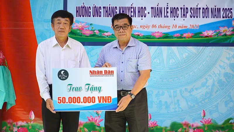 Ông Phạm Hữu Hoàn (bìa phải), đại diện Quỹ Xã hội Cỏ May trao 50 triệu đồng do Báo Nhân Dân vận động Quỹ để hỗ trợ học bổng tặng học sinh phường Thường Lạc.